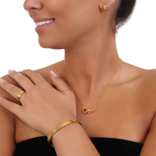Close-up of a woman wearing a queen's jewelry set featuring a gold necklace, earrings, bangle, and ring.